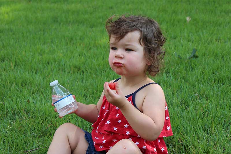 toddler with watermelon and bottled water